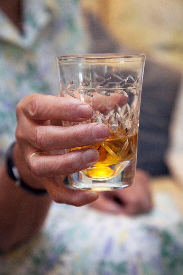 Glass of sherry in elderly woman's hand