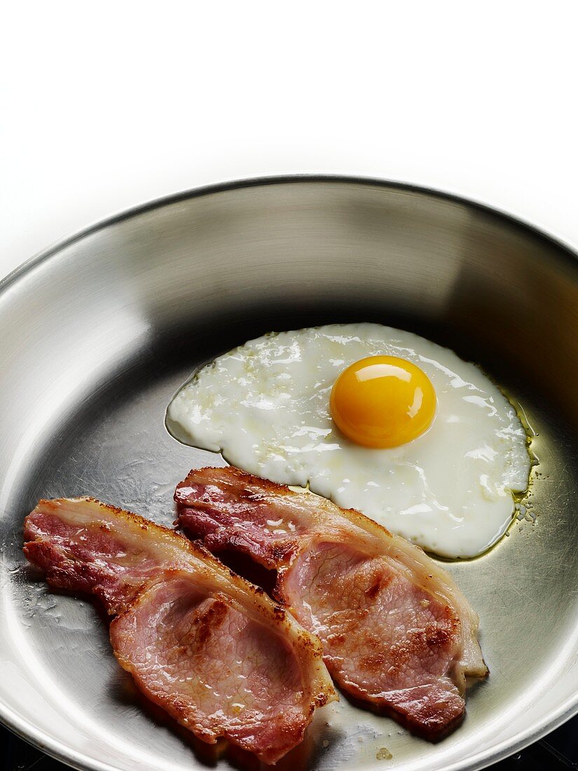 Bacon and eggs cooking in a frying pan