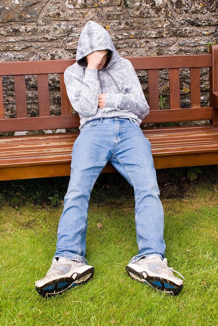 Depressed teenage boy on park bench