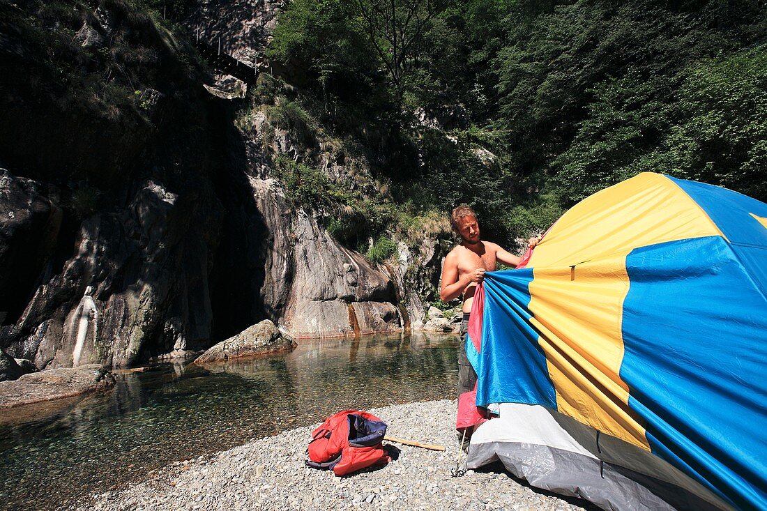 Man erecting a tent by a river