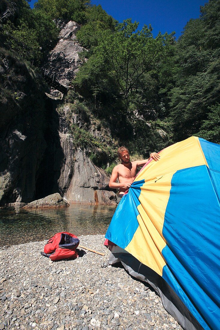 Man erecting a tent by a river