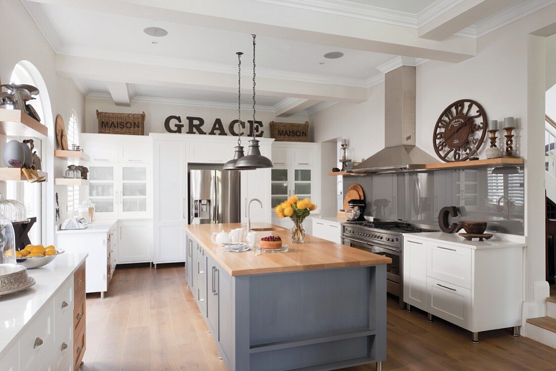 Spacious, open-plan kitchen; central counter with wooden worksurface on grey-painted base unit