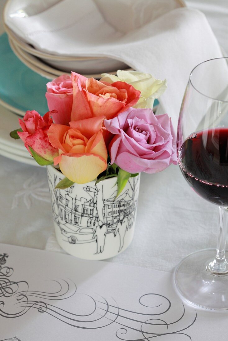 Table centrepiece of roses next to glass of red wine