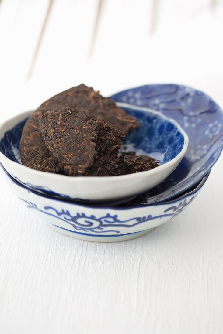 A piece of a pu-erh tea brick in a blue-and-white bowl