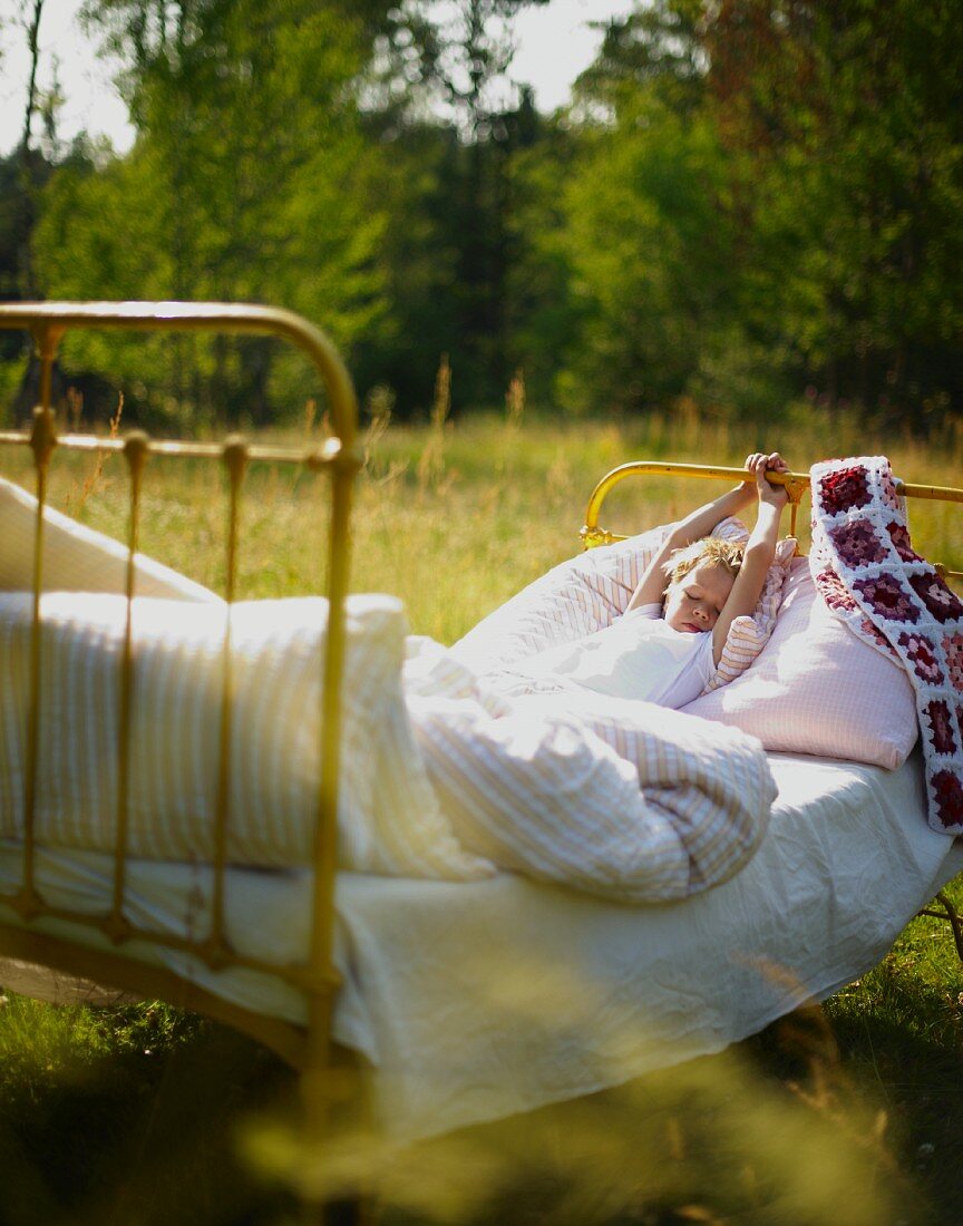 Child waking up in bed in meadow