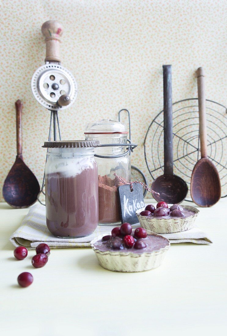 Jars of chocolate pudding with cream and cranberries in chocolate sauce