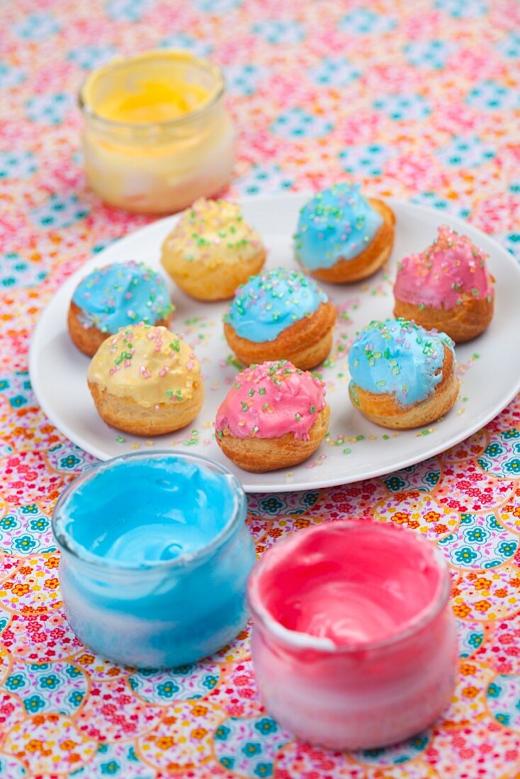 Profiteroles with colourful icing and sugar sprinkles