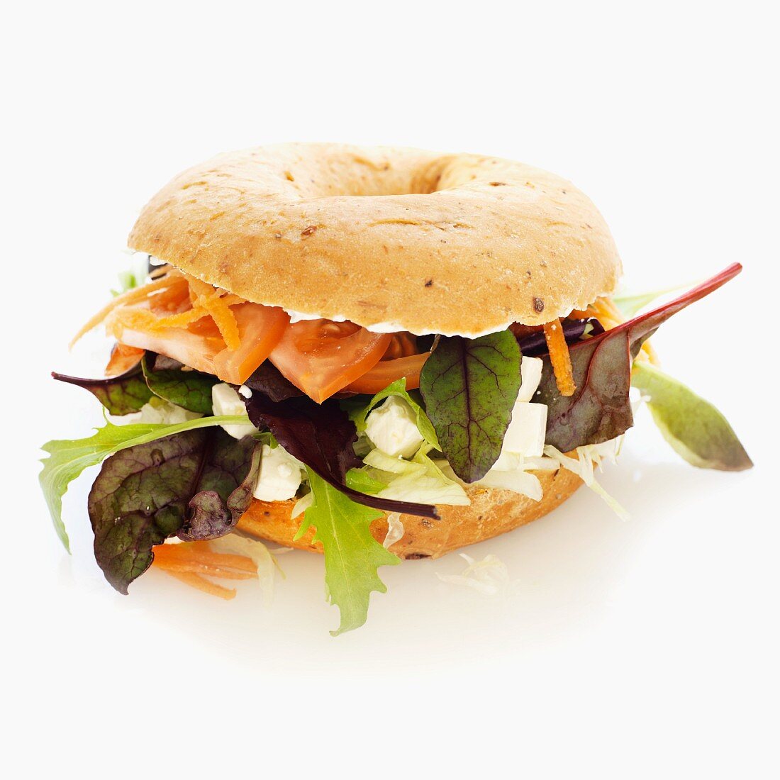 A bagel with feta cheese, lettuce, tomato and carrot