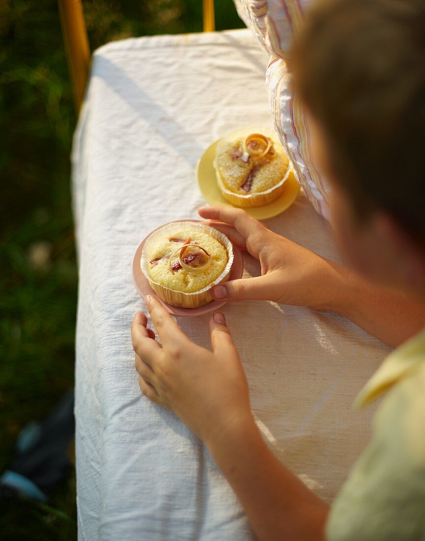 A boy eating a muffin for breakfast in bed in a field