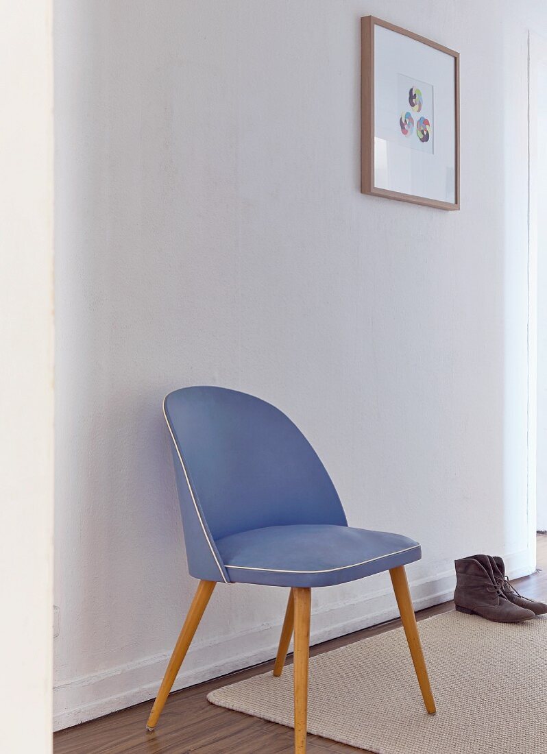 Blauer Fifty Stuhl vor weisser Wand im schlichten weißen Flur