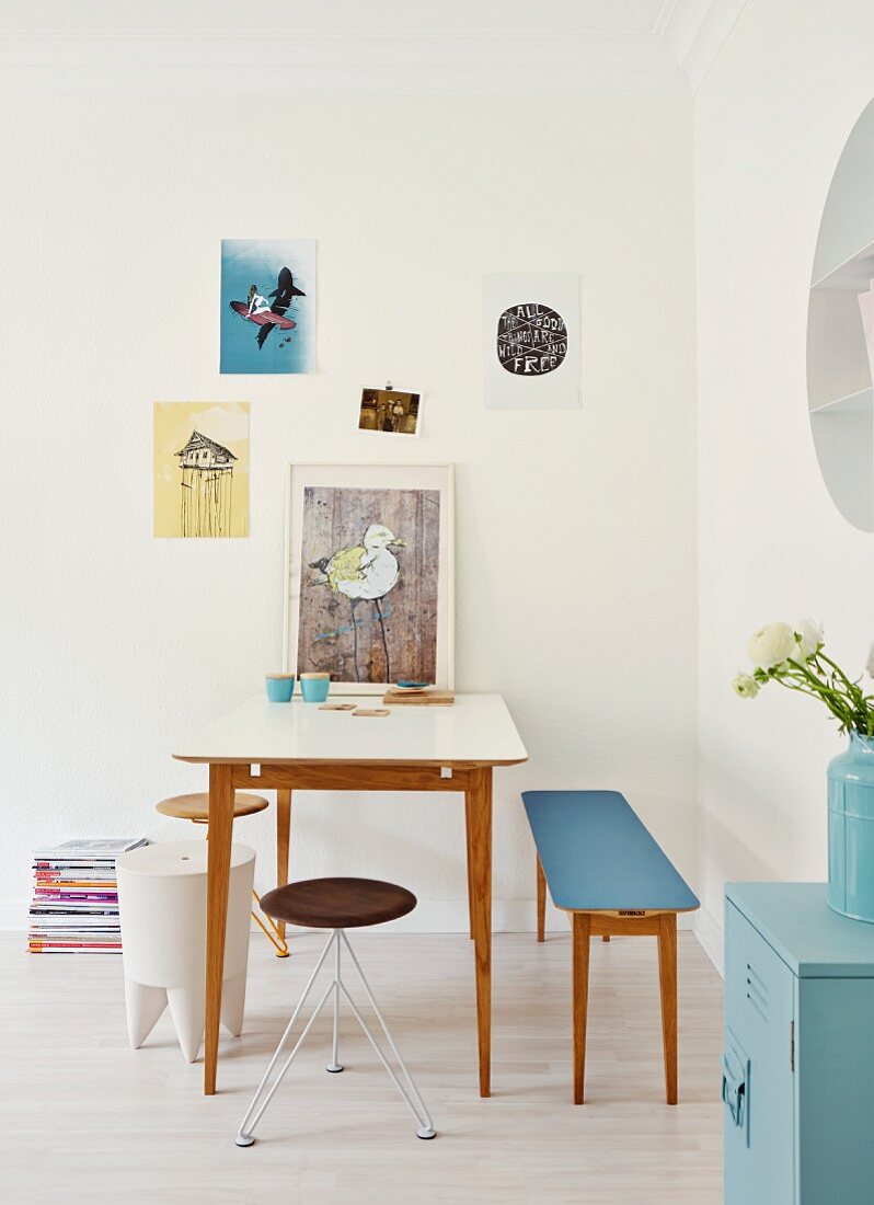Youthful dining area with delicate, designer furnishings and small posters on wall