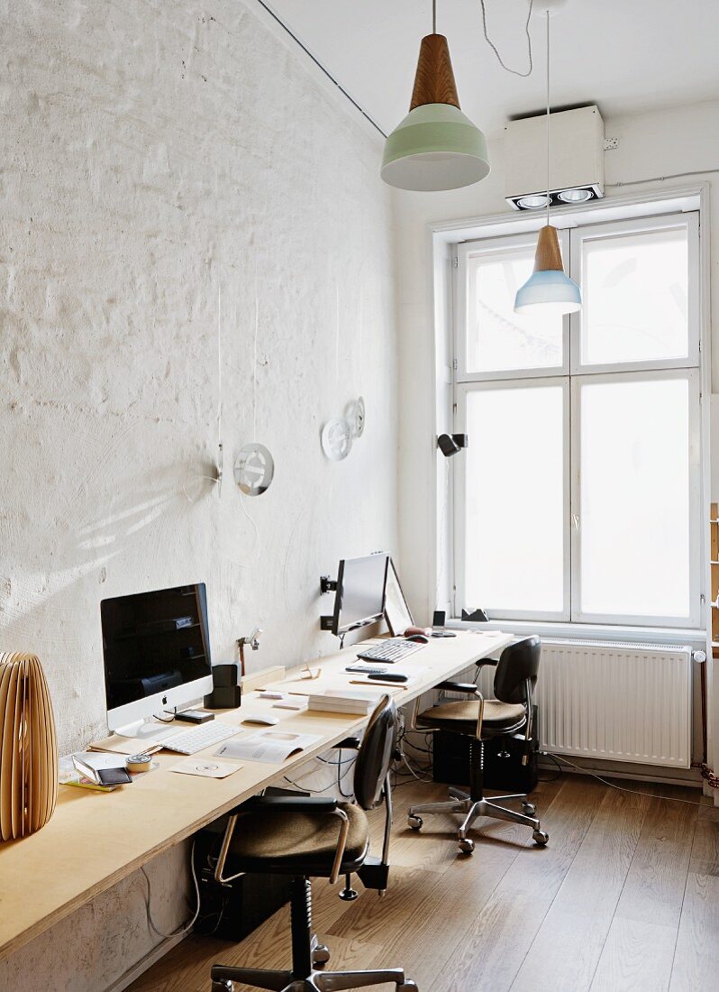 Büro mit langer Arbeitsplatte für zwei Personen und Vintage Schreibtischstühle vor der Wand, in minimalistischem Ambiente mit traditionellem Flair