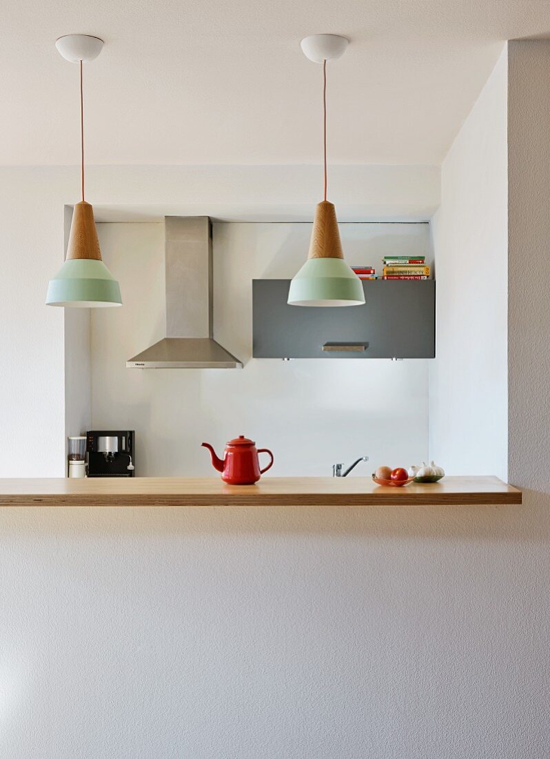 Küchentheke mit Holz Arbeitsplatte unter Hängeleuchten-Reihe in offener Küche mit minimalistischem Flair