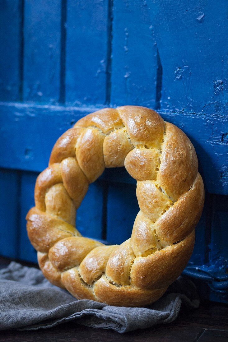 A brioche wreath leaning against a blue wooden door