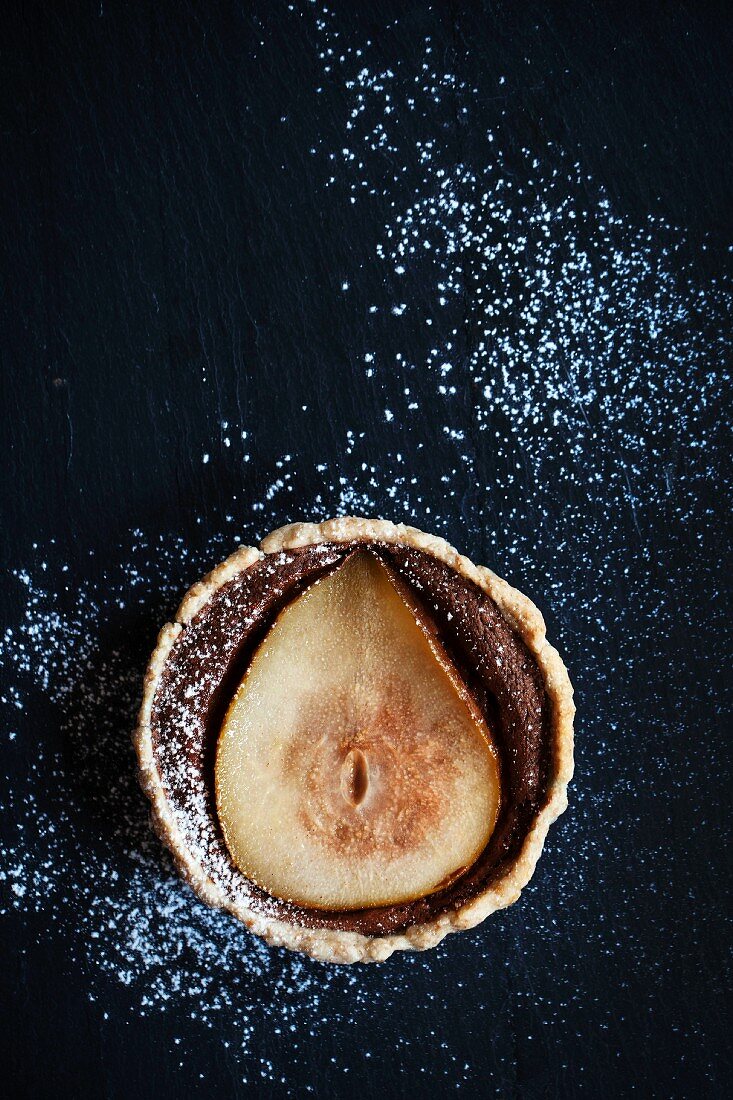 Pear and chocolate tart with icing sugar