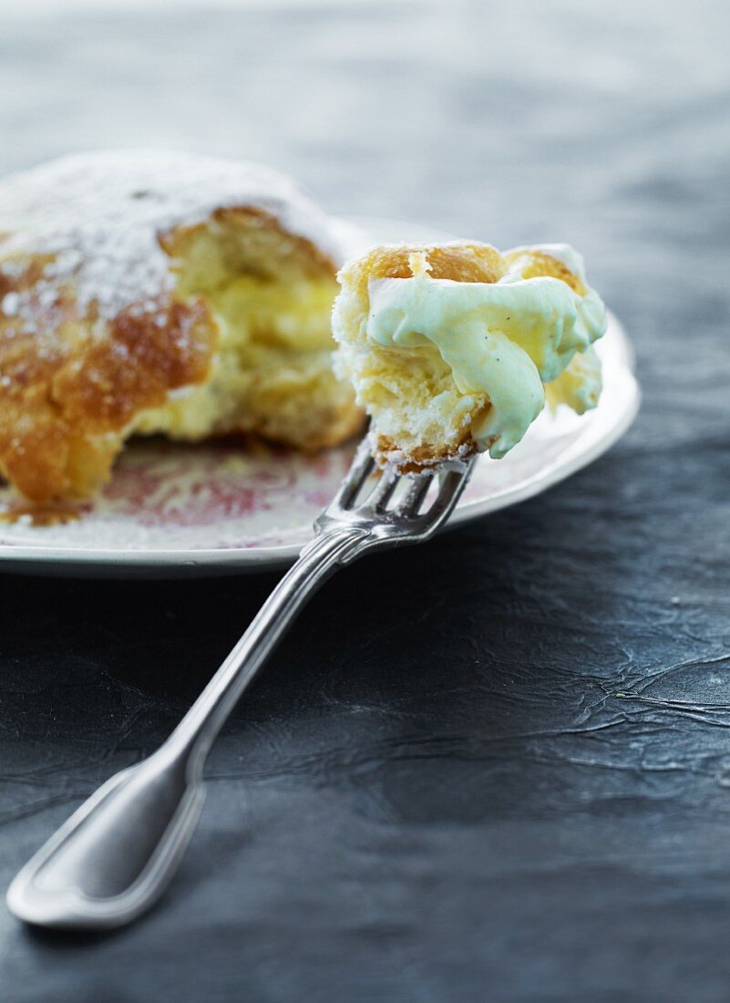 A Buchtel (baked, sweet yeast dumpling) with vanilla sauce and a bite taken out