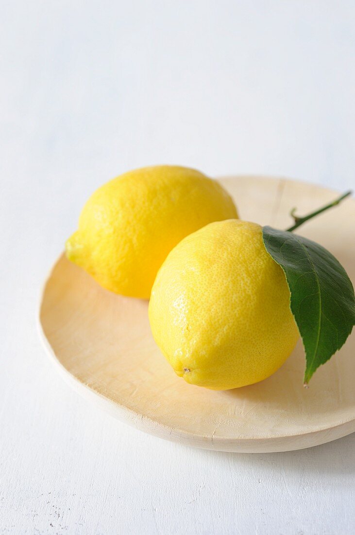 Two lemons on a wooden plate