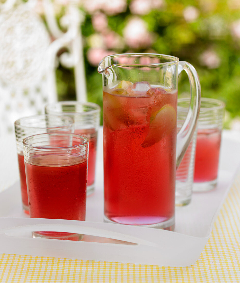 Berry juice with lines and ice cubes in a jug and in glasses