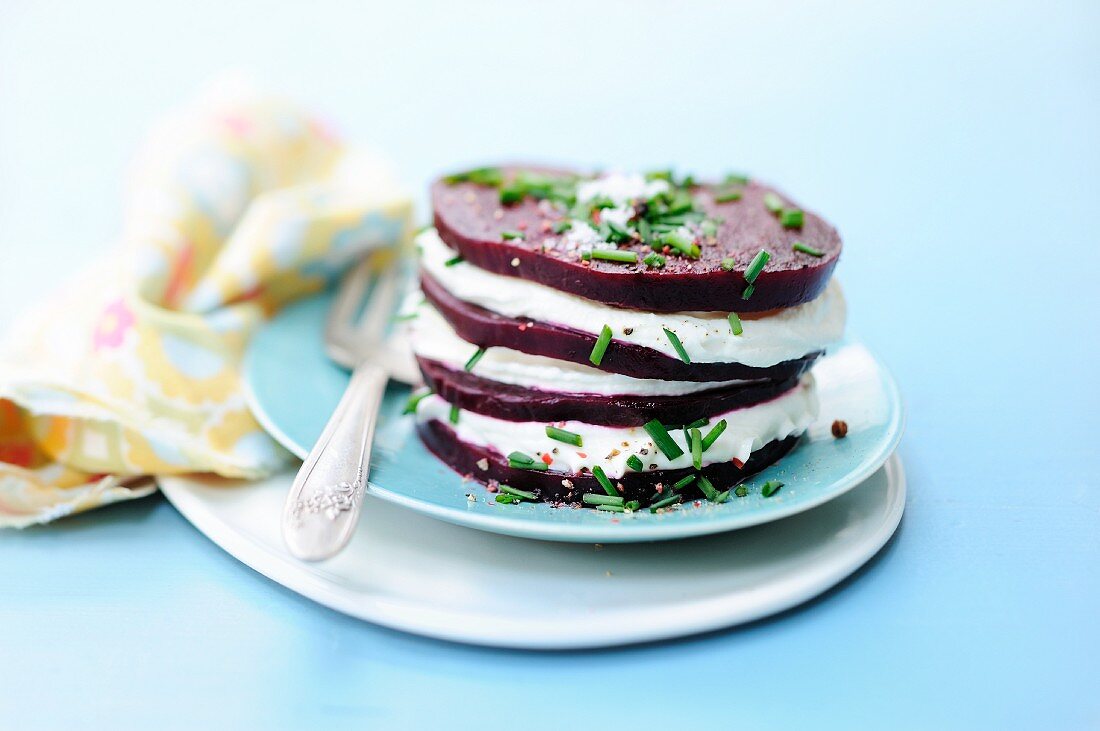 A stack of beetroot slices held together with cream cheese and garnished with chives