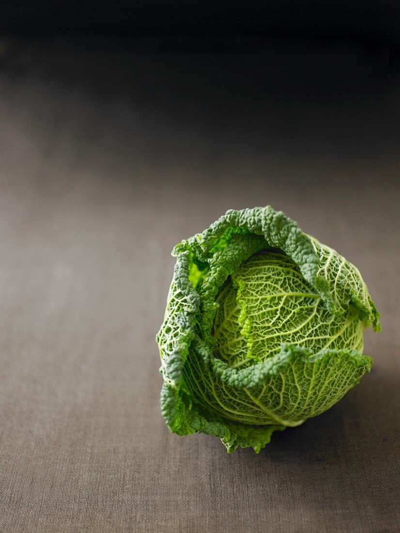A Savoy cabbage on a grey surface