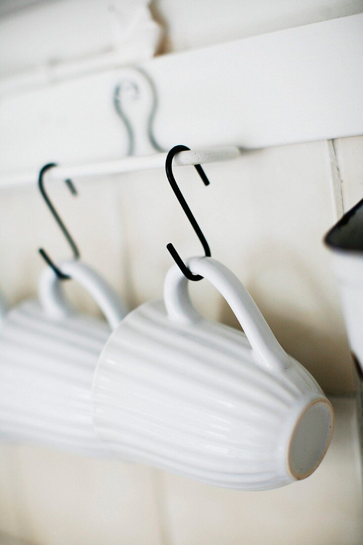 White mugs hanging from hooks