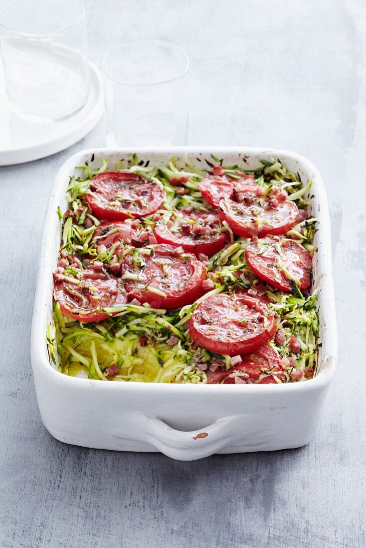 Potato cake in a baking dish with tomato and courgette