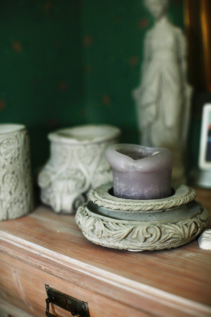 Verzierter Kerzenhalter aus Stein mit violetter Stumpenkerze