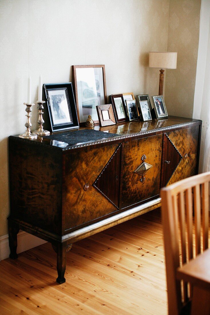 Collection of framed photos on Biedermeier-style, antique sideboard in corner