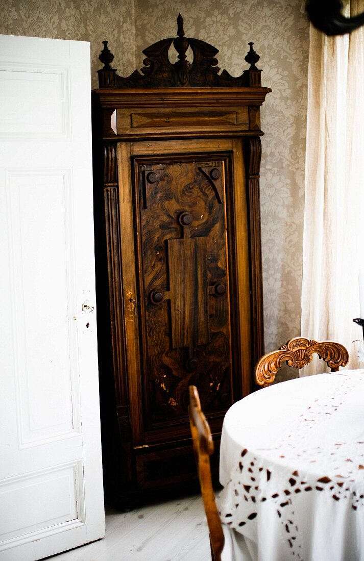 Antique cupboard with carved moulding behind dining set