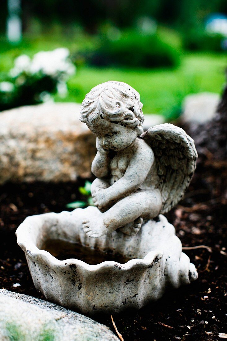 Stone bird bath with cherub figurine outside
