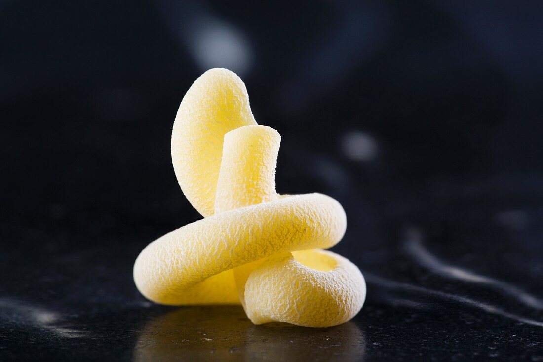 A piece of fresh Vesuvio pasta standing on a dark marble surface