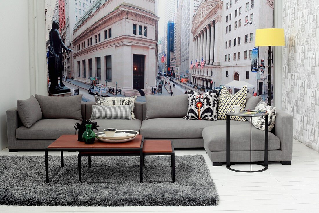 Set of coffee tables and grey sofa in front of New York mural wallpaper