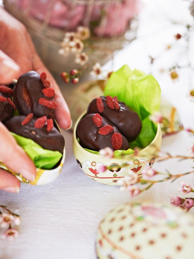 Frauenhände stellen Schokoladeneier auf den Ostertisch