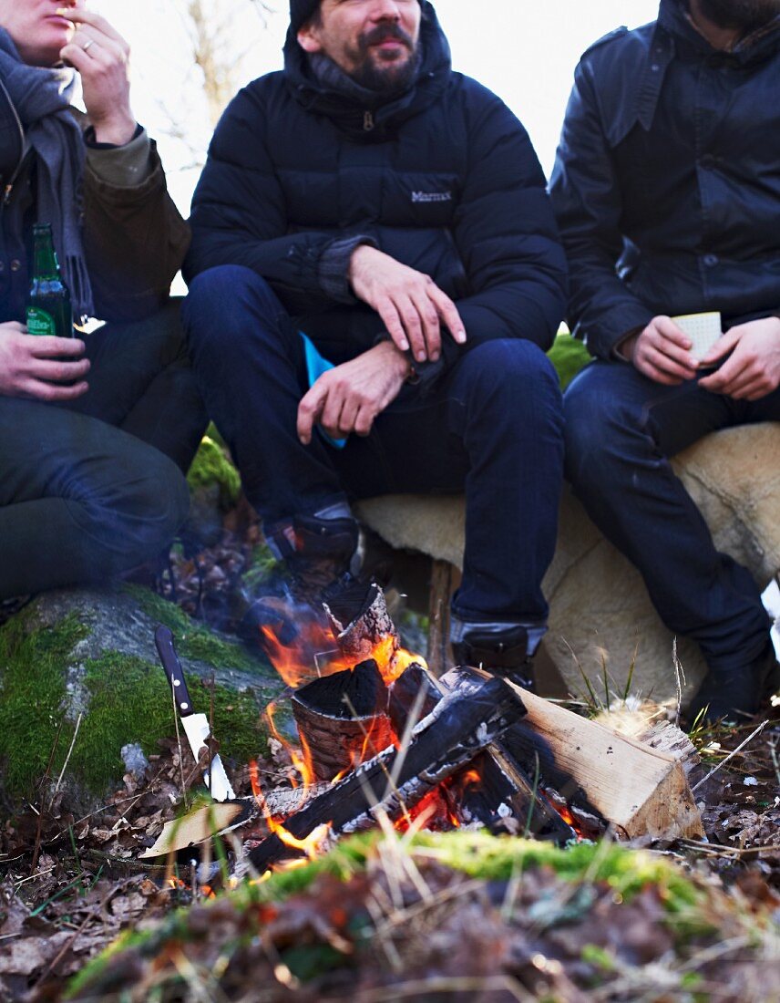 Three men sitting by a campfire in winter