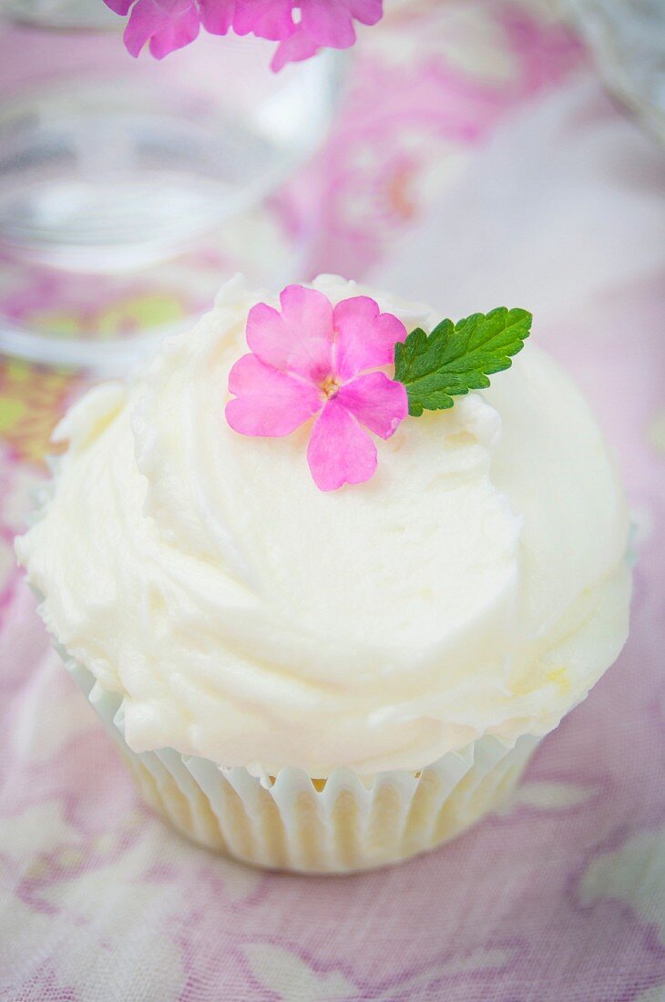 A lemon cupcake with buttercream and decorated with a flower