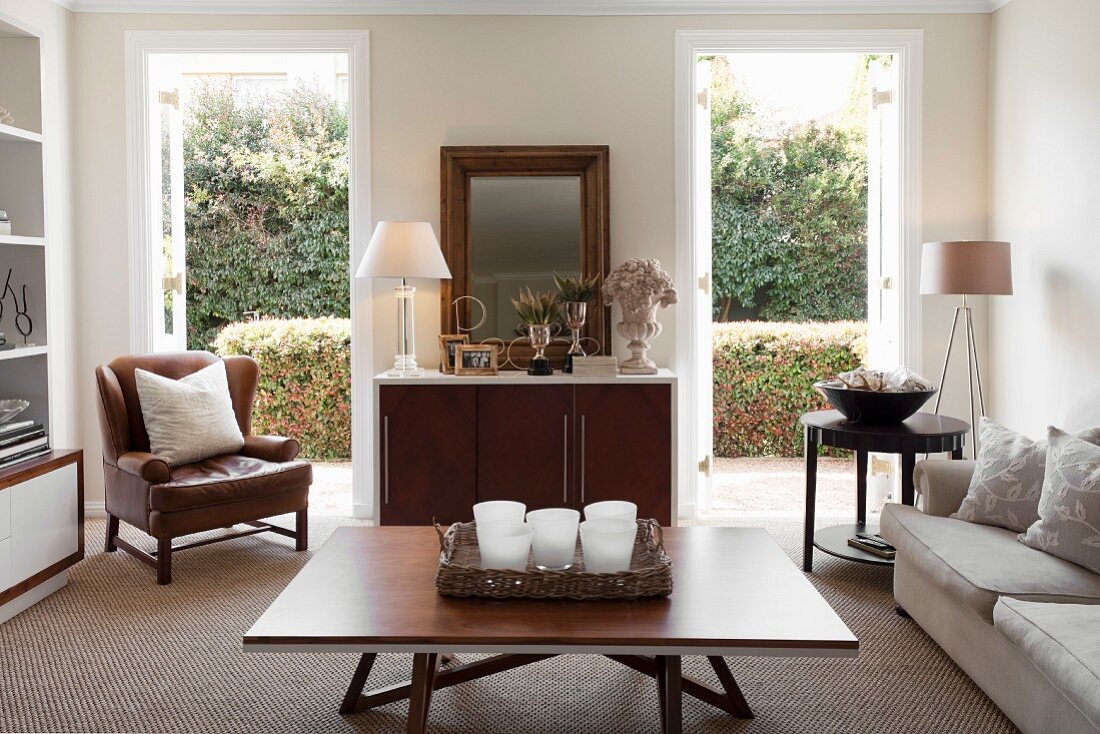 Modern coffee table, tealight holders on tray and sideboard flanked by open terrace doors