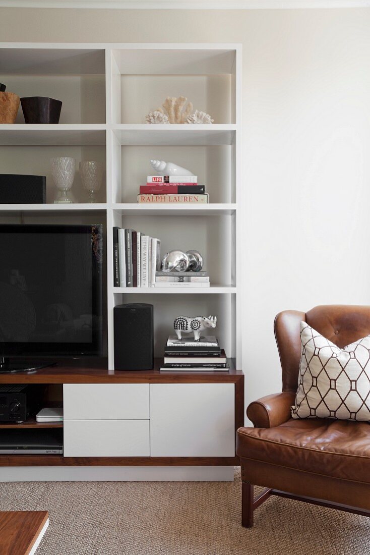 Brown leather armchair next to modern, white shelving