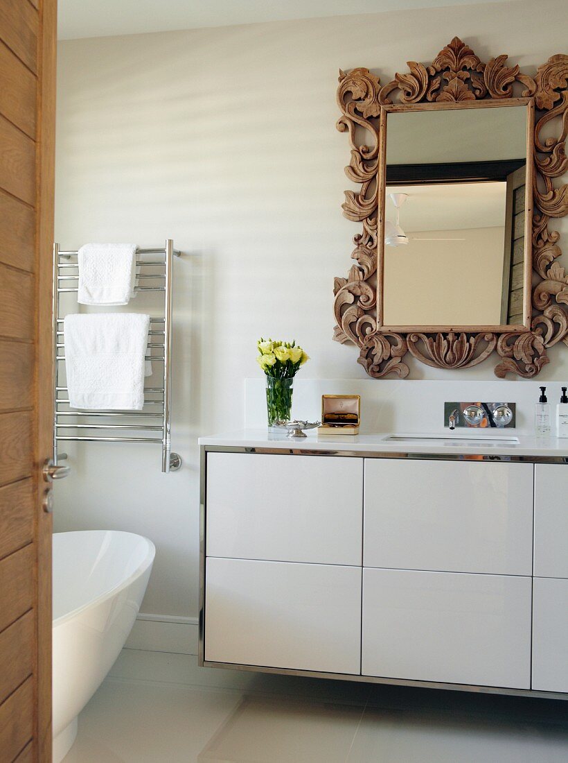 Modern washstand with white base unit below mirror with ornate wooden frame