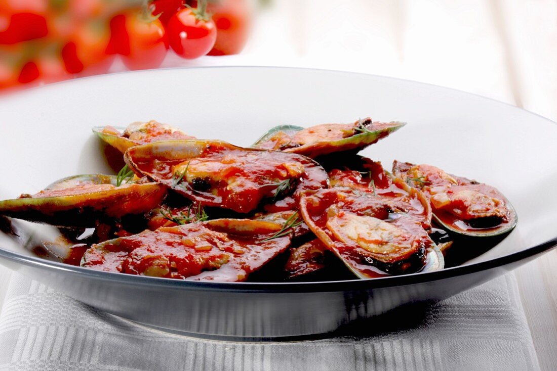 Mussels with tomato sauce on a black plate