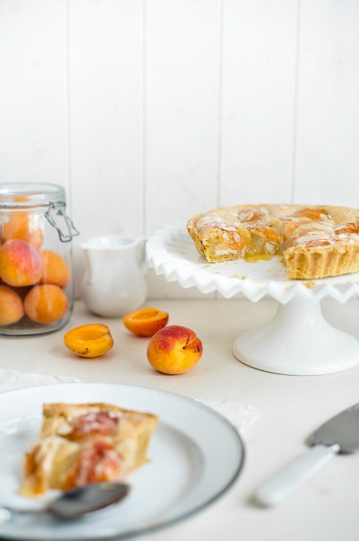 Angeschnittener Aprikosen-Pie mit Mandelblättchen, ein Stück auf Teller