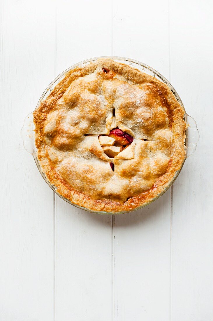 A whole plum pie in a glass dish seen from above