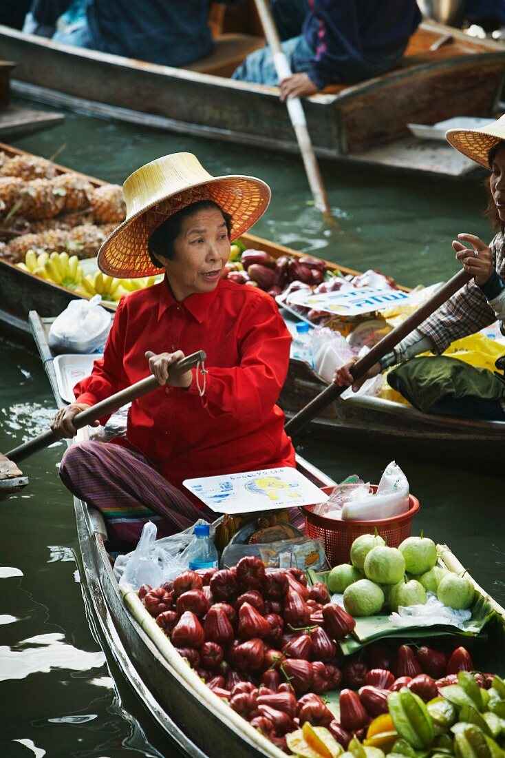 A Thai market stall holder on a floating vegetable stand