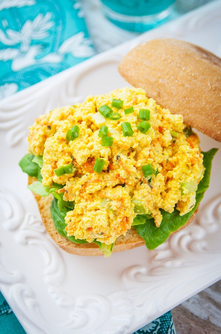 Brötchenhälfte mit Tofu-Kurkuma-Salat und Frühlingszwiebeln