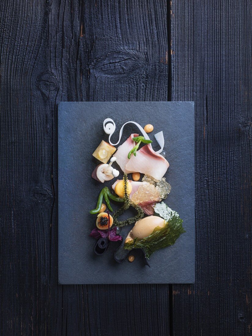 A hamachi platter with seaweed and a side of vegetables