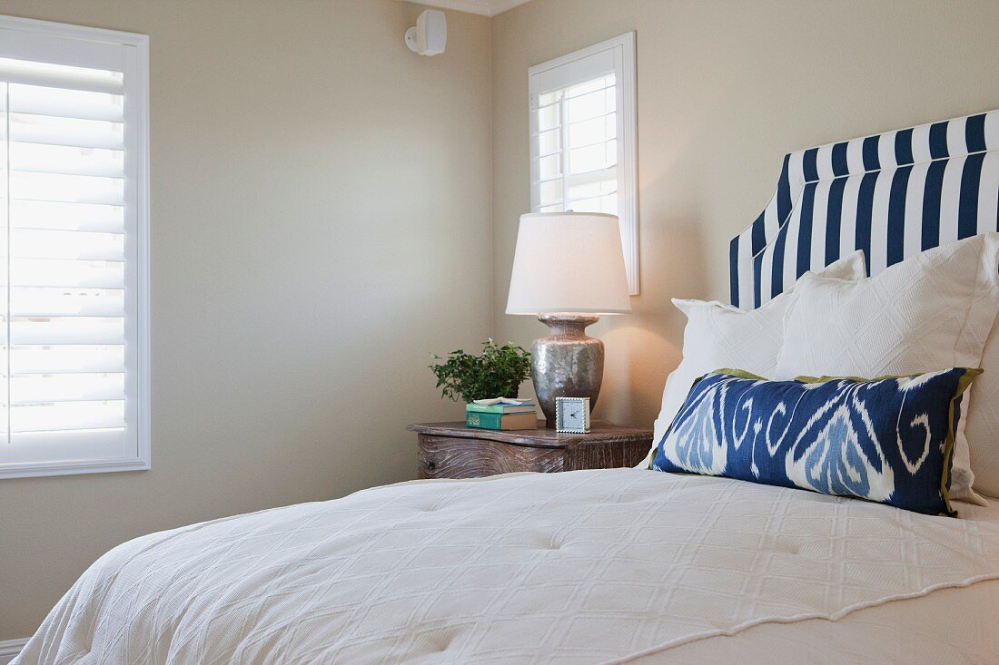 Arranged pillows on bed with lit table lamp in bedroom; California; USA