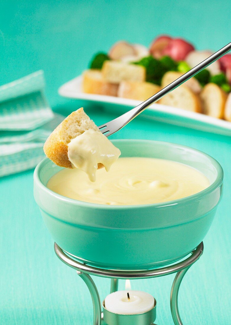A cheese fondue with bread and vegetables