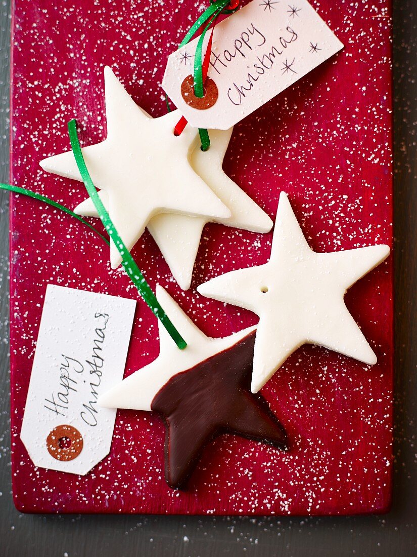 Star-shaped peppermint cream biscuits as gift tags on a red surface