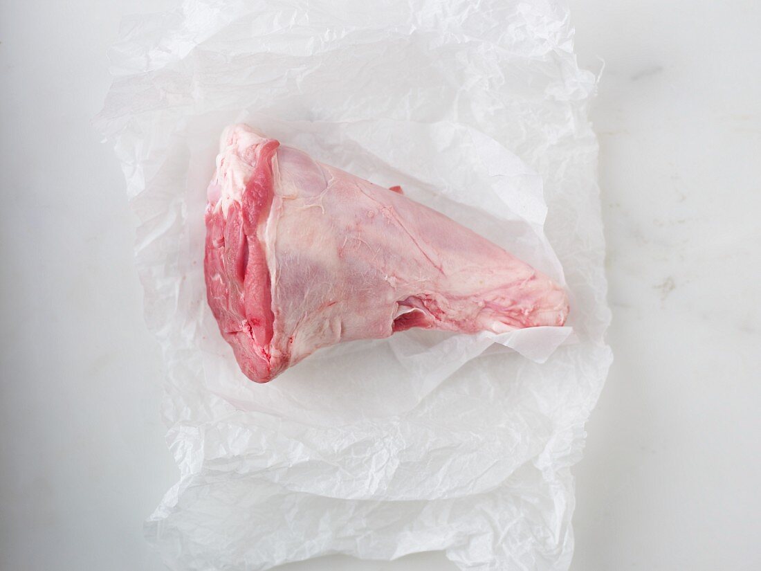 A raw leg of lamb on a piece of parchment paper