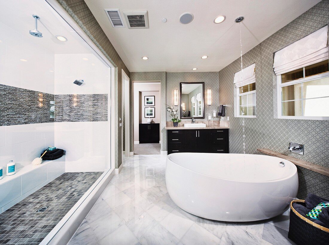 Freistehende, runde Badewanne auf Marmorboden gegenüber grosszügigem Duschbereich in traditionellem Ambiente