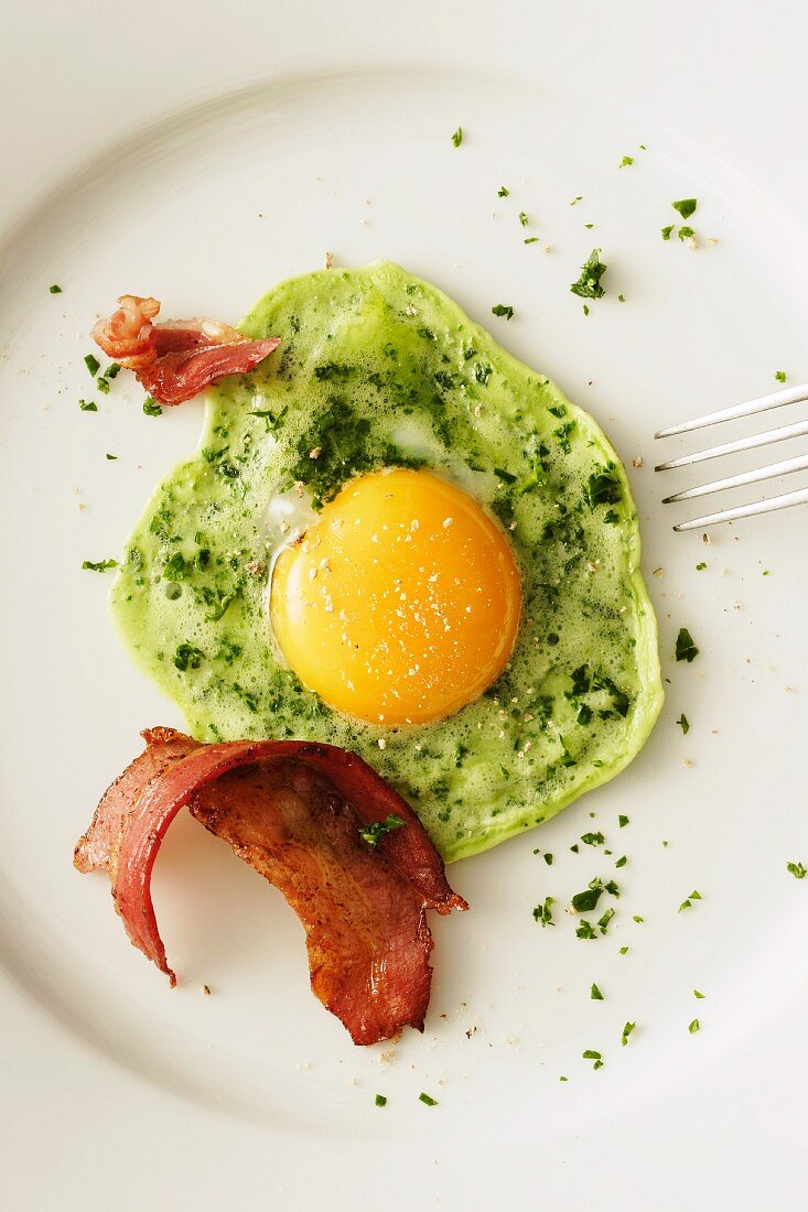 A green fried egg with bacon